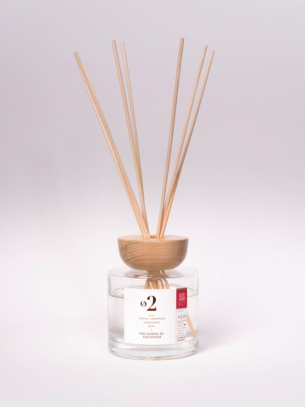 Reed diffuser with wooden sticks in a clear container on a white background