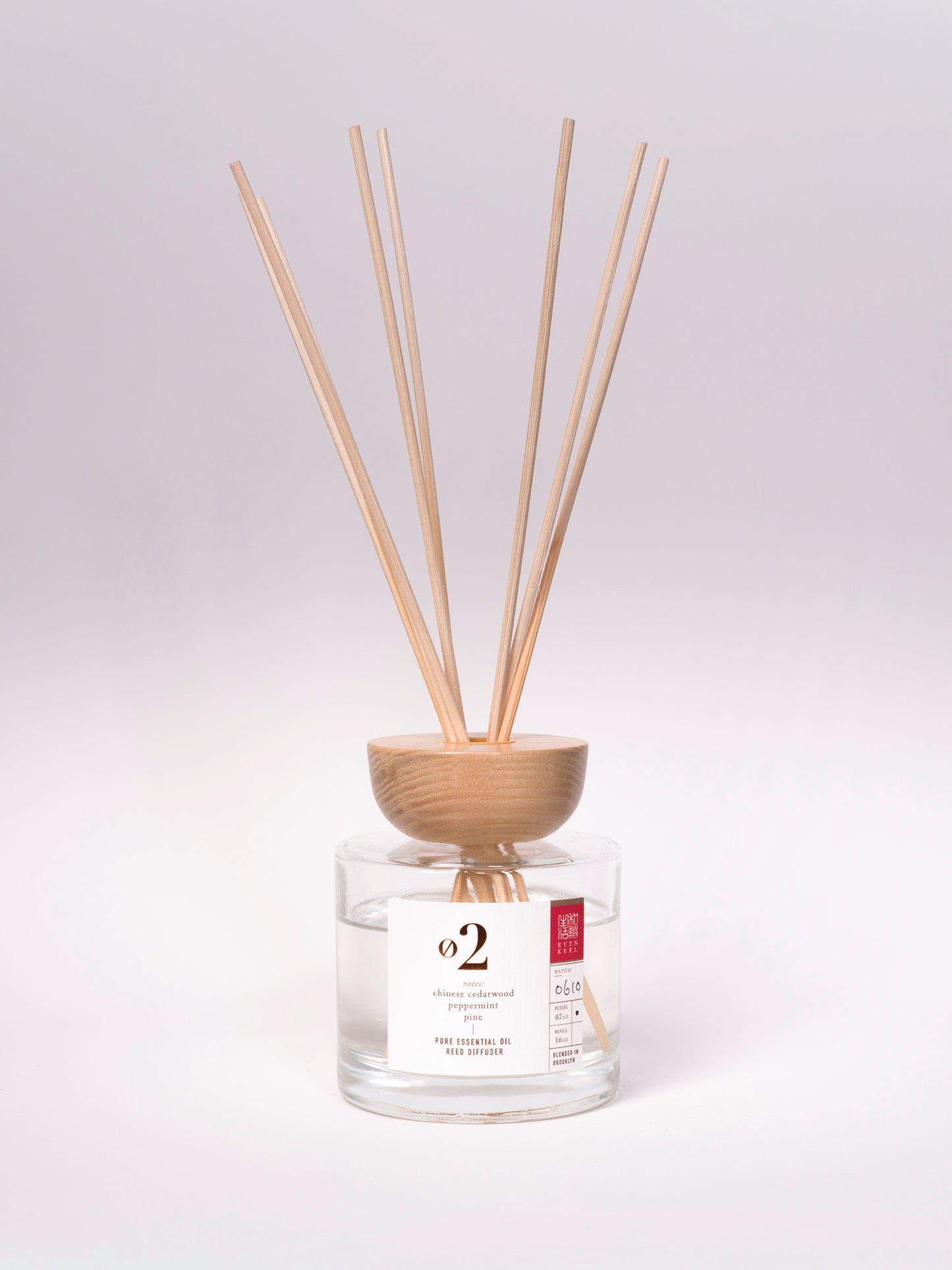 Reed diffuser with wooden sticks in a clear container on a white background